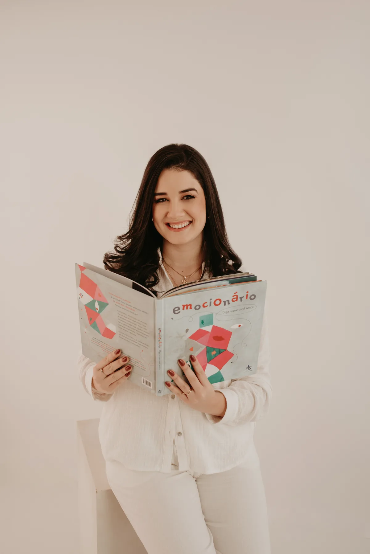 Thais sorrindo enquanto segura um livro ilustrado