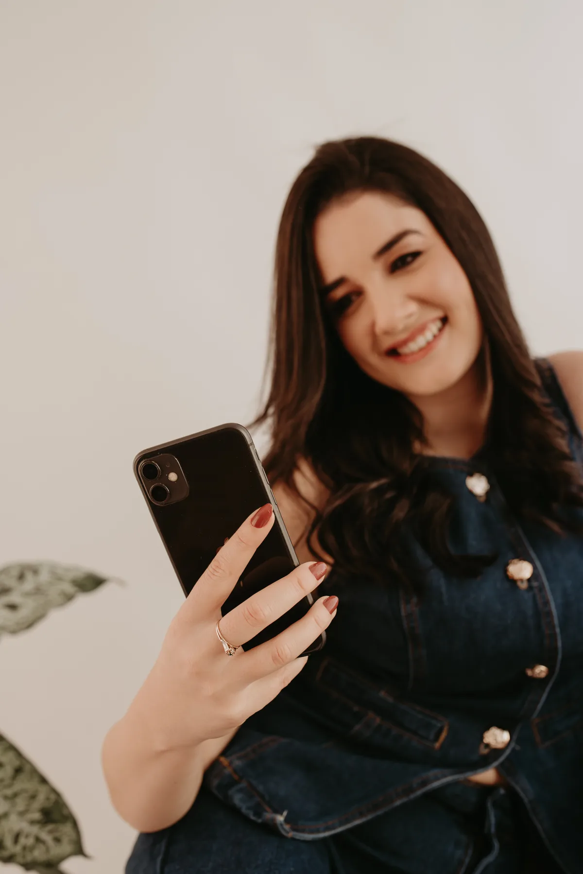 Thais segurando um celular durante seu ensaio profissional
